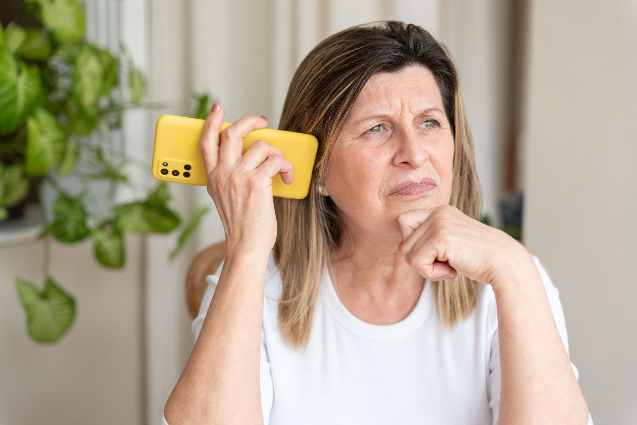 Woman holding a phone and looking away, illustrating caregiver burnout.